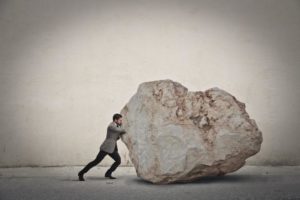 Business person pushing a big rock
